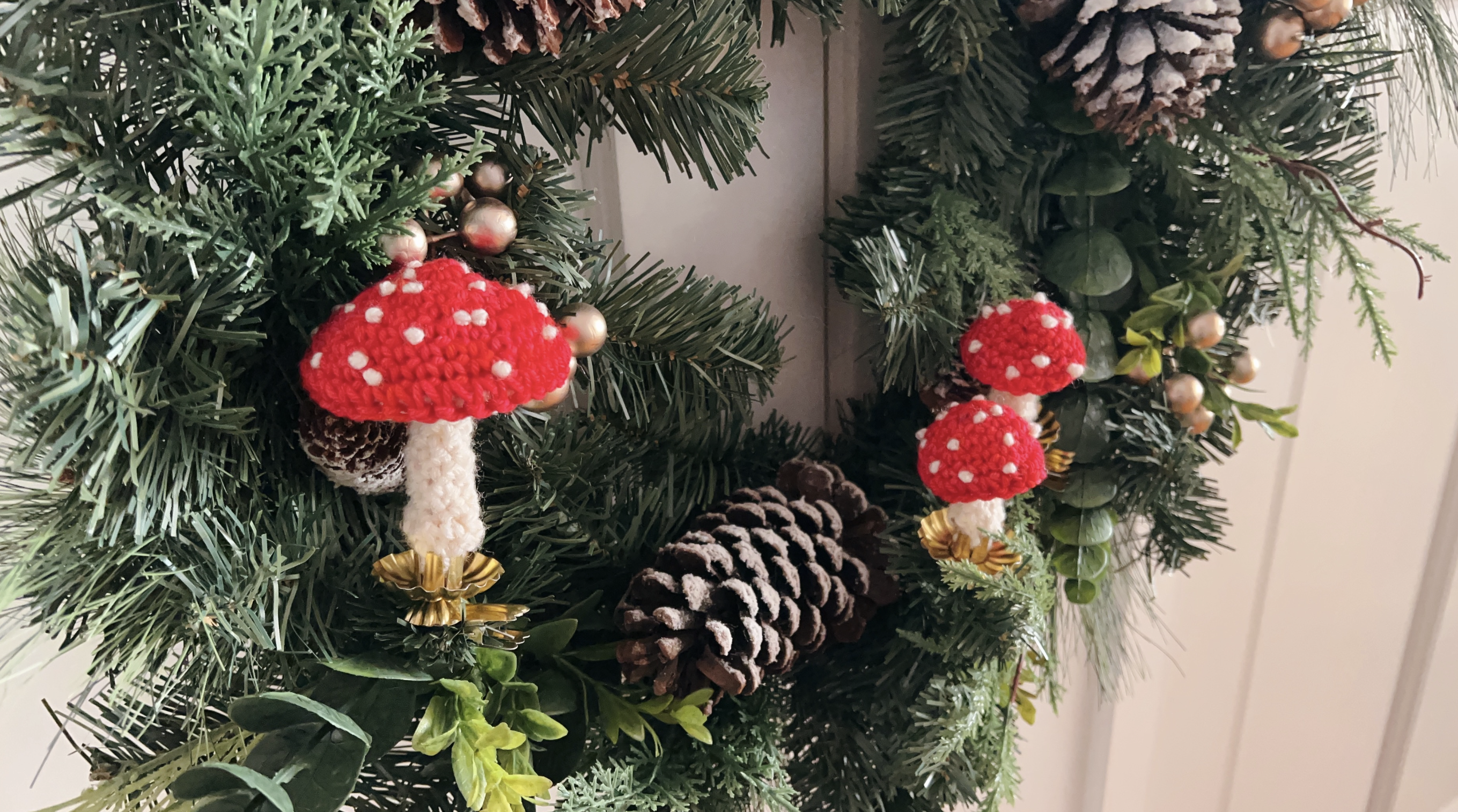 image of crocheted toadstools clipped onto a holiday wreath with gold candle clips